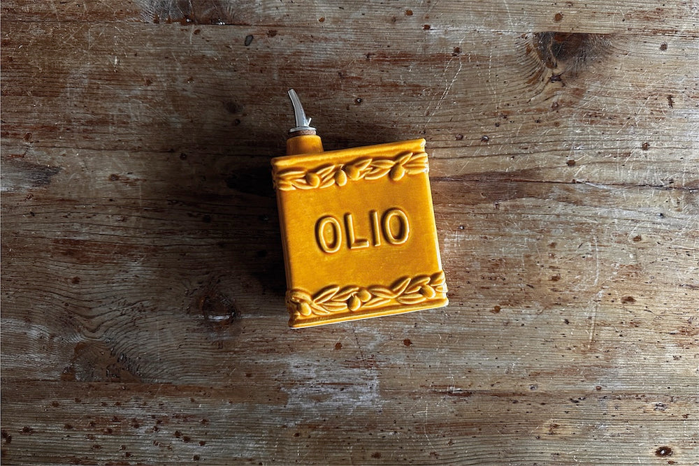 Honey-coloured handmade ceramic oil bottle with embossed Olio d’Oliva detail and cork stopper, rustic Italian tableware